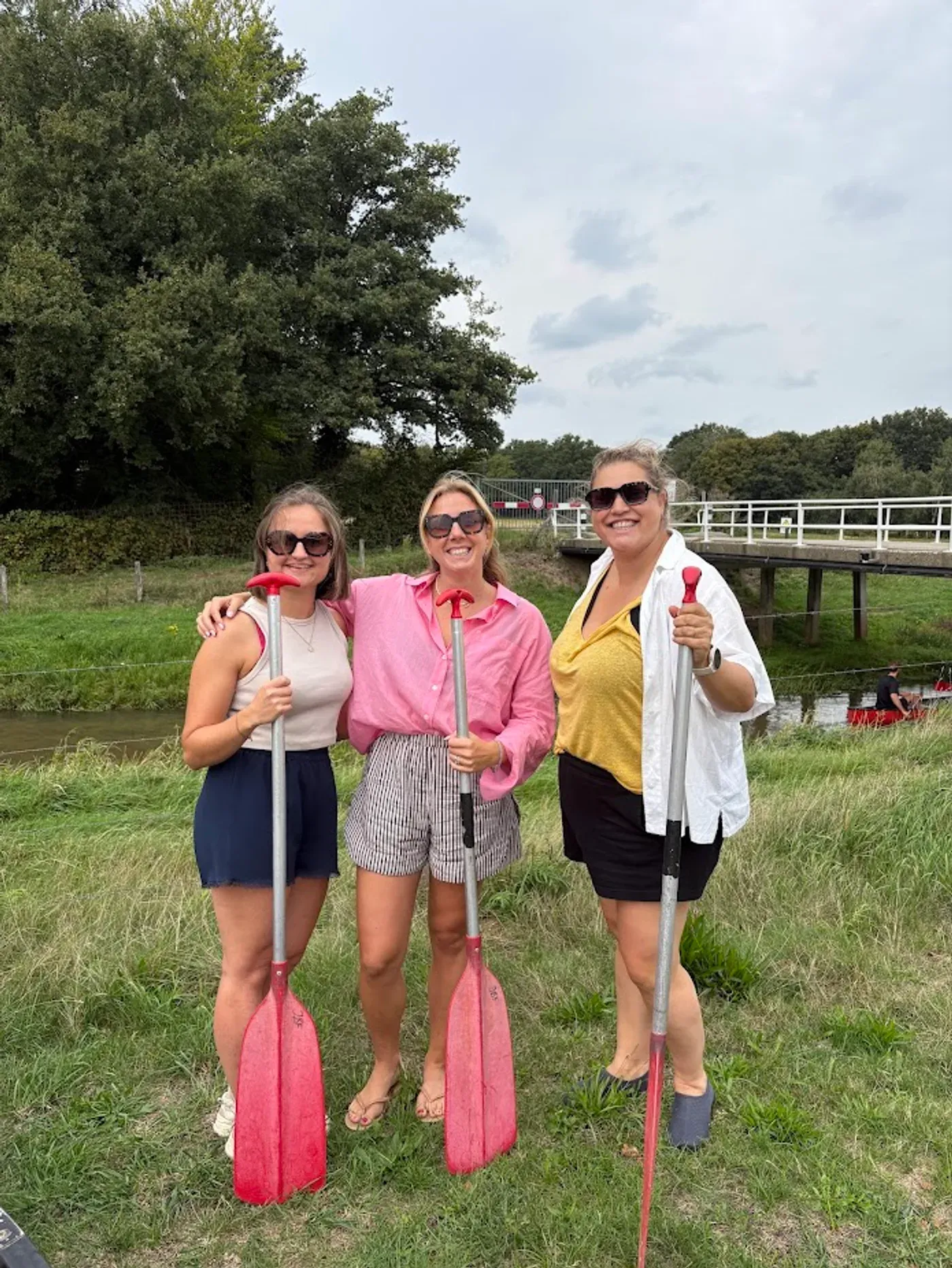 Drie Harmony-collega's met peddels aan de waterkant.