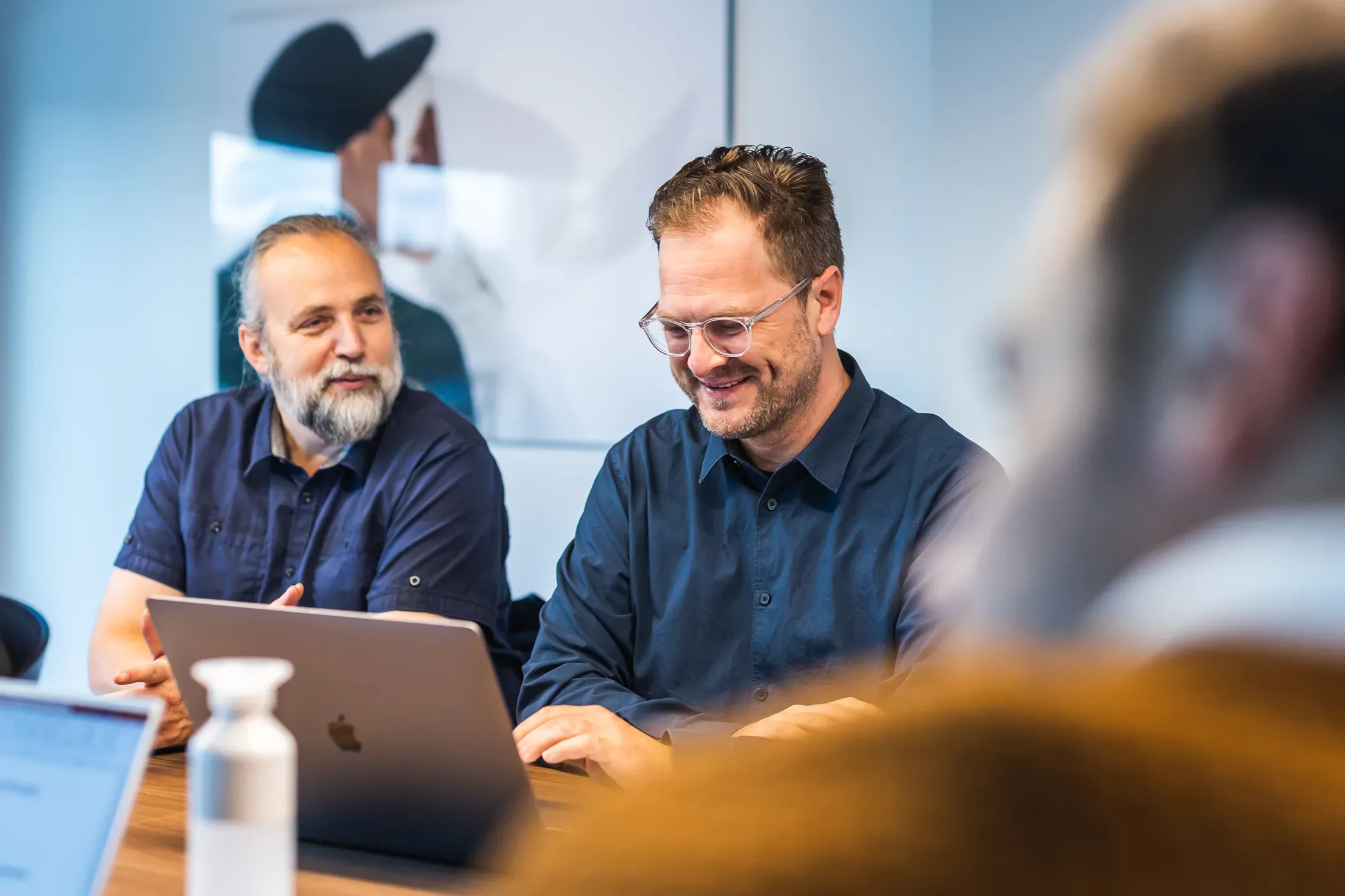 Twee consultants van Harmony in overleg aan een tafel met laptops.